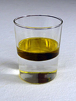 An image of a thick layer of oil floating on water in an ordinary glass